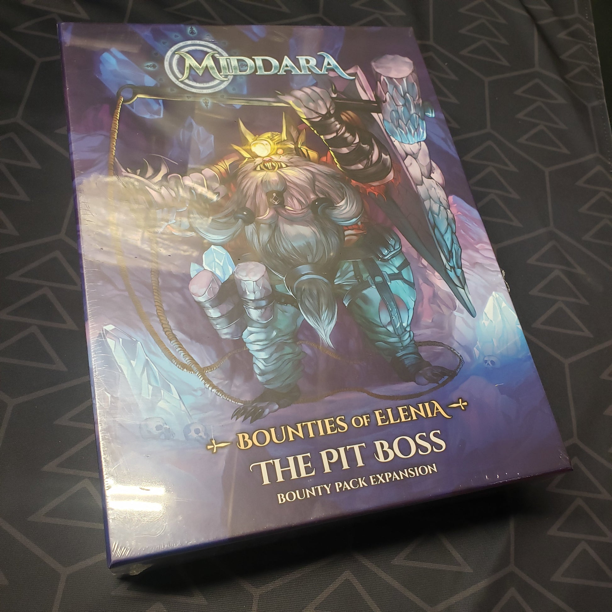 Image shows the front cover of the box of the Bounties of Elenia: The Pit Boss Bounty Pack expansion for the board game Middara