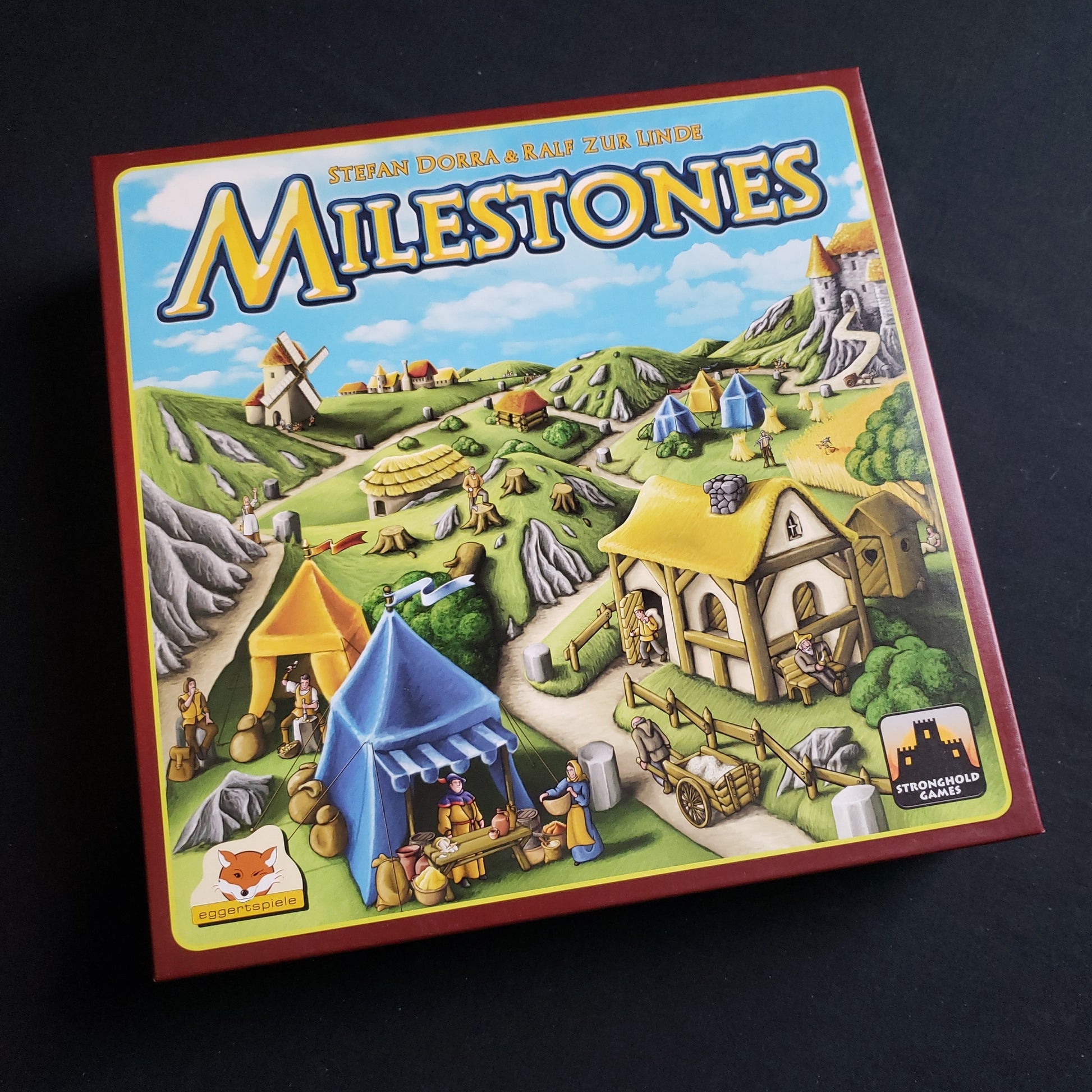 Image shows the front cover of the box of the Milestones board game