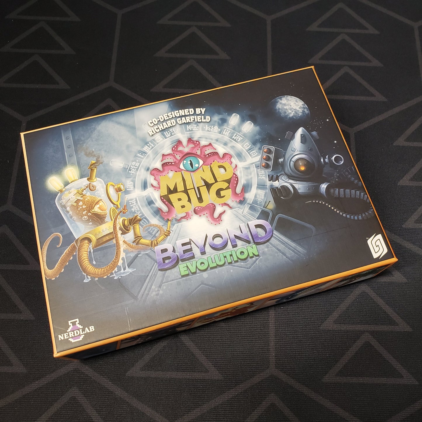 Image shows the front cover of the box of the Mindbug: Beyond Evolution card game