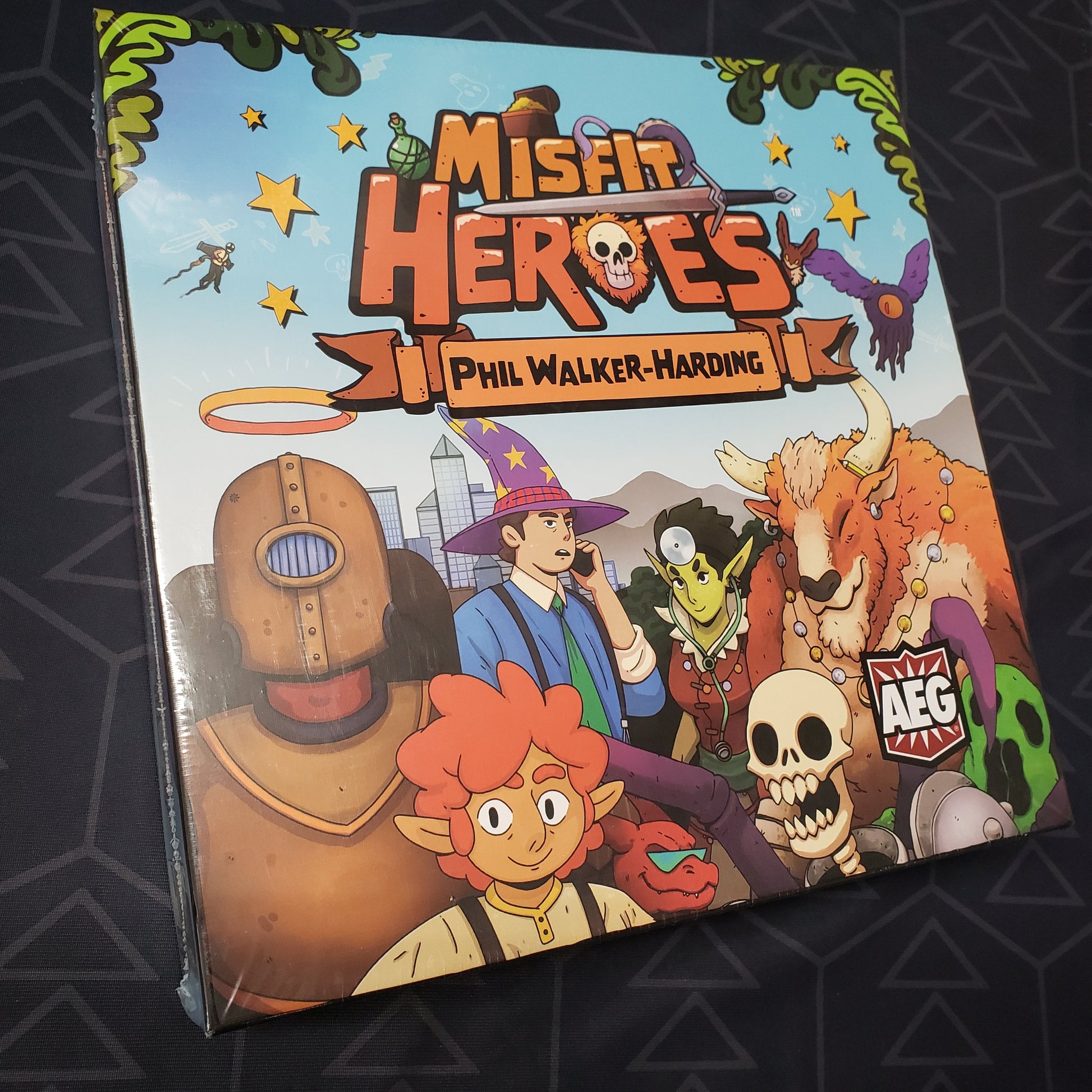Image shows the front cover of the box of the Deluxe Upgrade Pack expansion for the card game Misfit Heroes