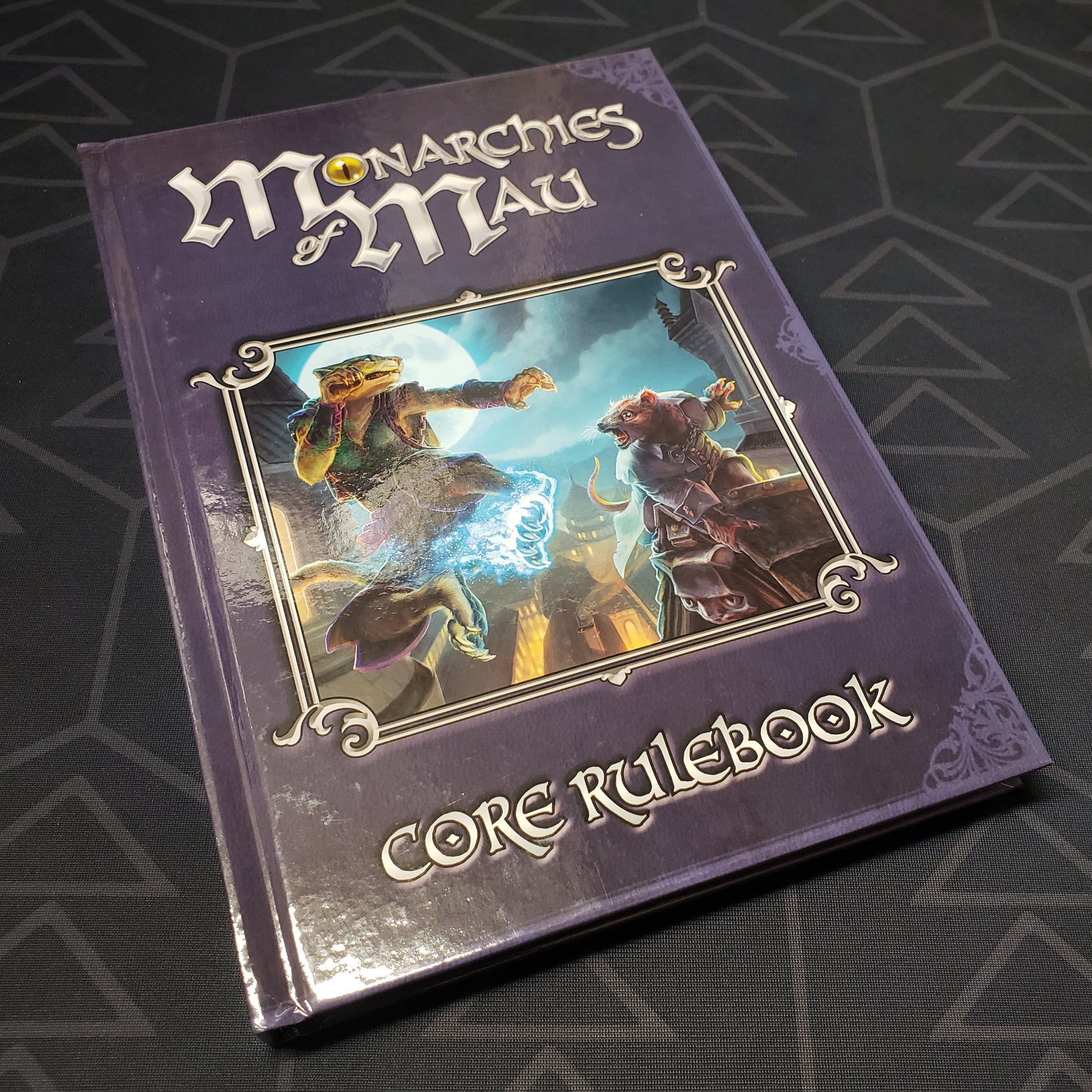 Image shows the front cover of the core rulebook for the roleplaying game Monarchies of Mau