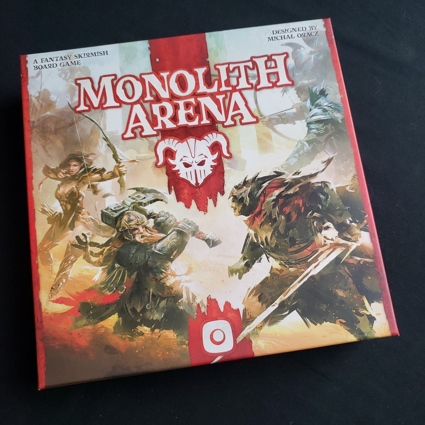 Image shows the front cover of the box of the Monolith Arena board game