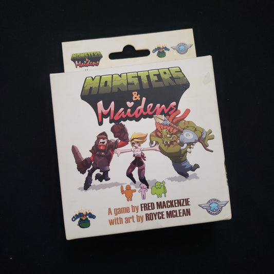 Image shows the front cover of the box of the Monsters & Maidens board game