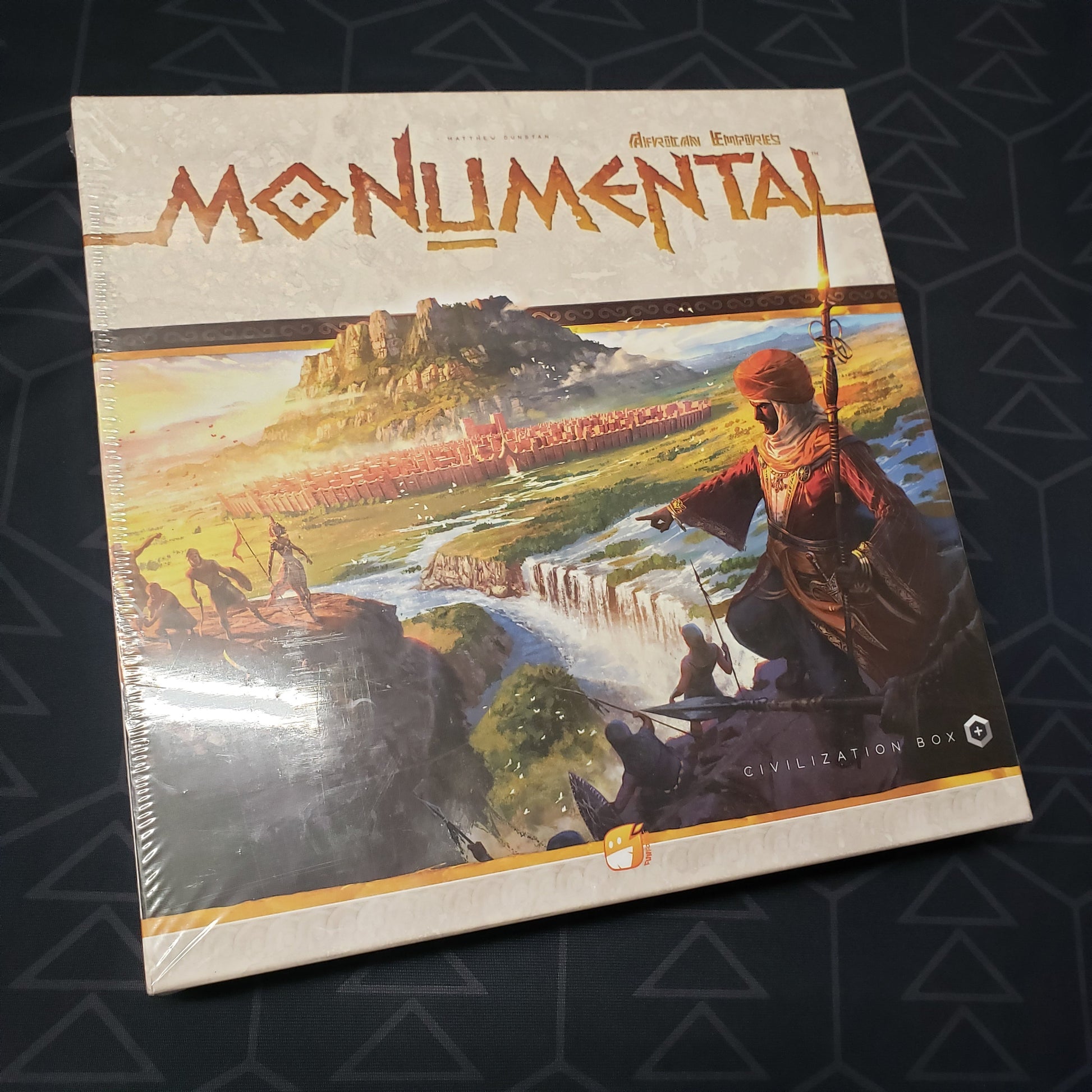 Image shows the front cover of the box of the African Empires expansion for the board game Monumental