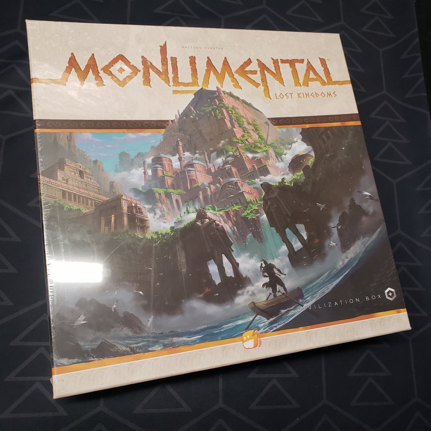Image shows the front cover of the box of the Lost Kingdoms expansion for the board game Monumental