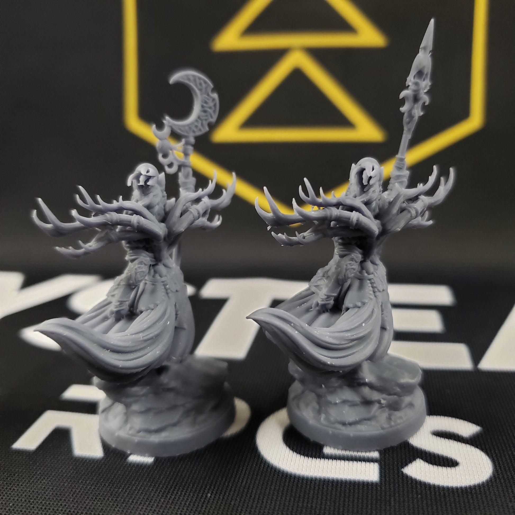 Image shows the back sides of two different weapon options of a 3D printed wolf warrior gaming miniature, one with a crescent moon staff and one with a spear.