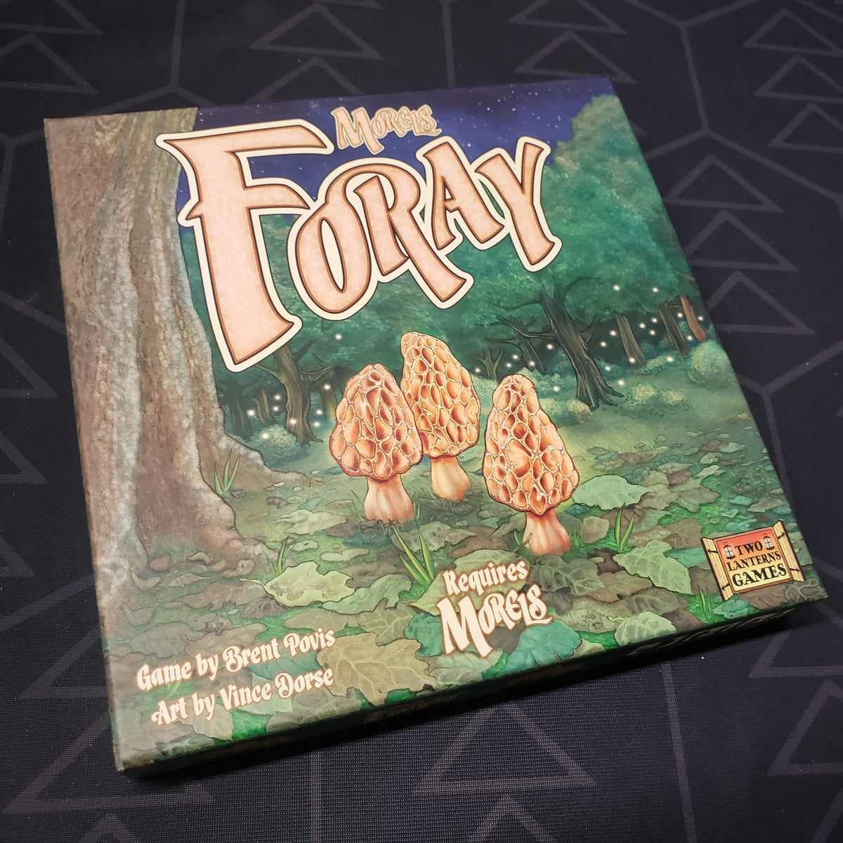 Image shows the front cover of the box of the Foray expansion for the card game Morels