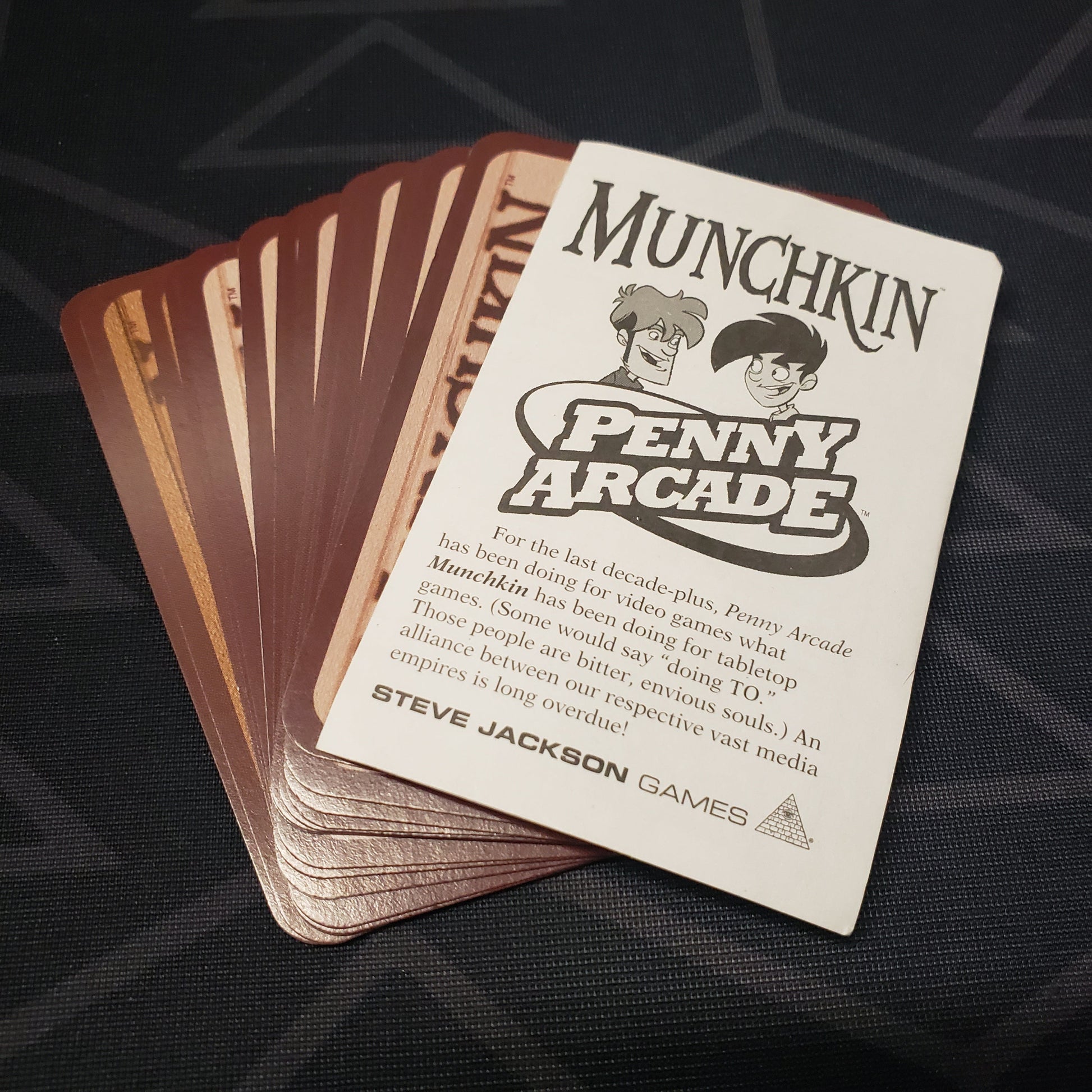 Image shows the instructions & fanned-out cards for the Penny Arcade expansion for the card game Munchkin