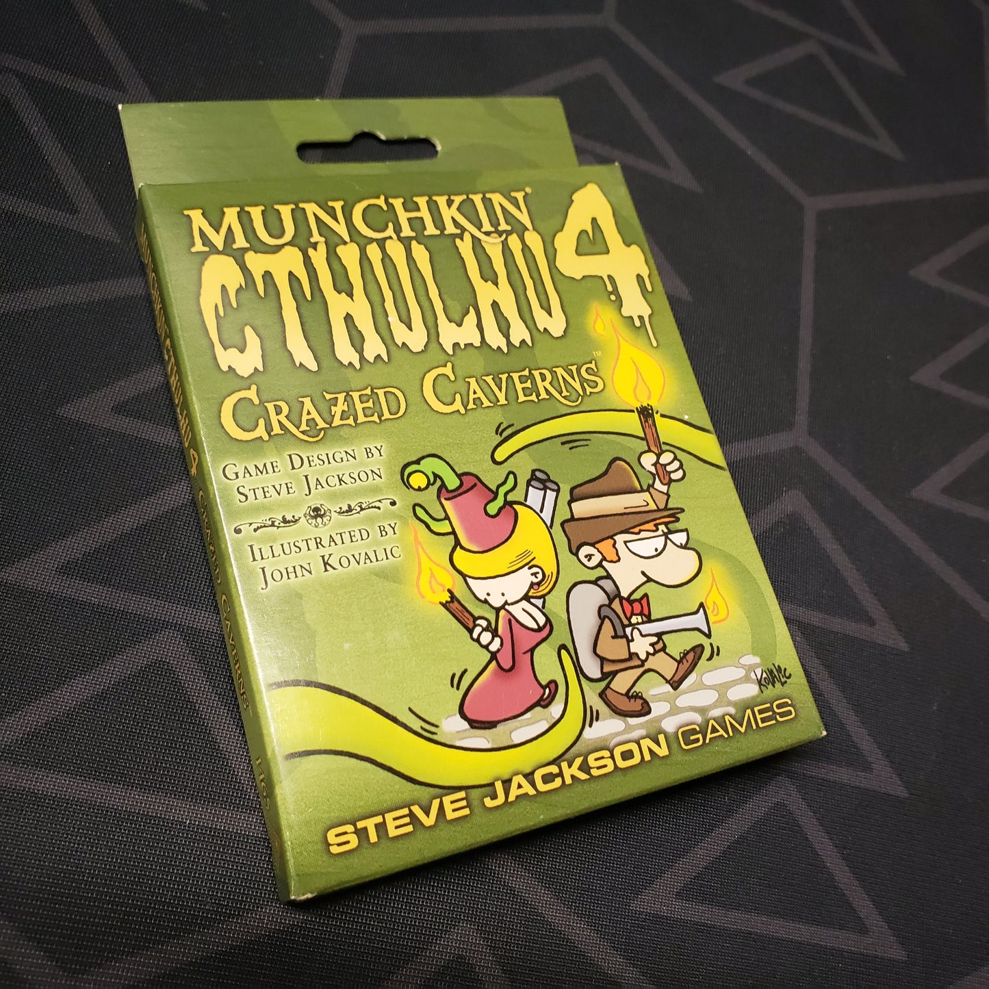 Image shows the front cover of the box of the Crazed Caverns expansion for the card game Munchkin Cthulhu