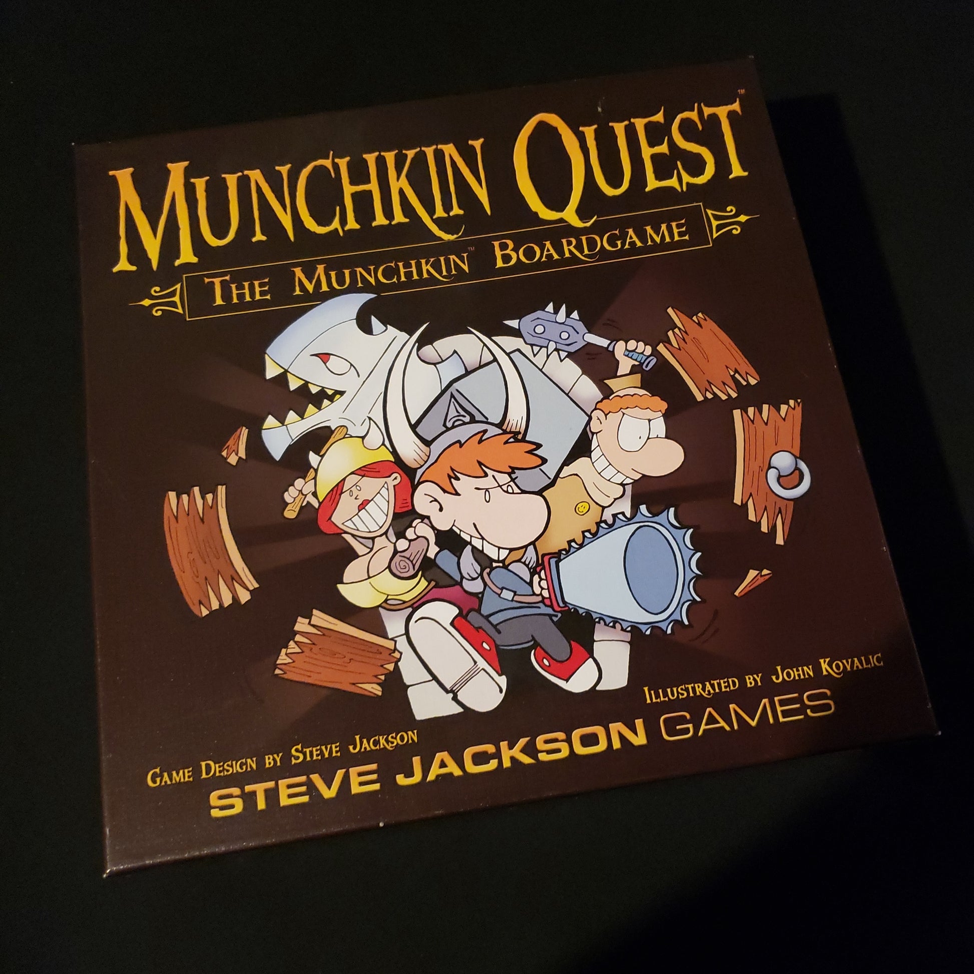 Image shows the front cover of the box of the Munchkin Quest board game