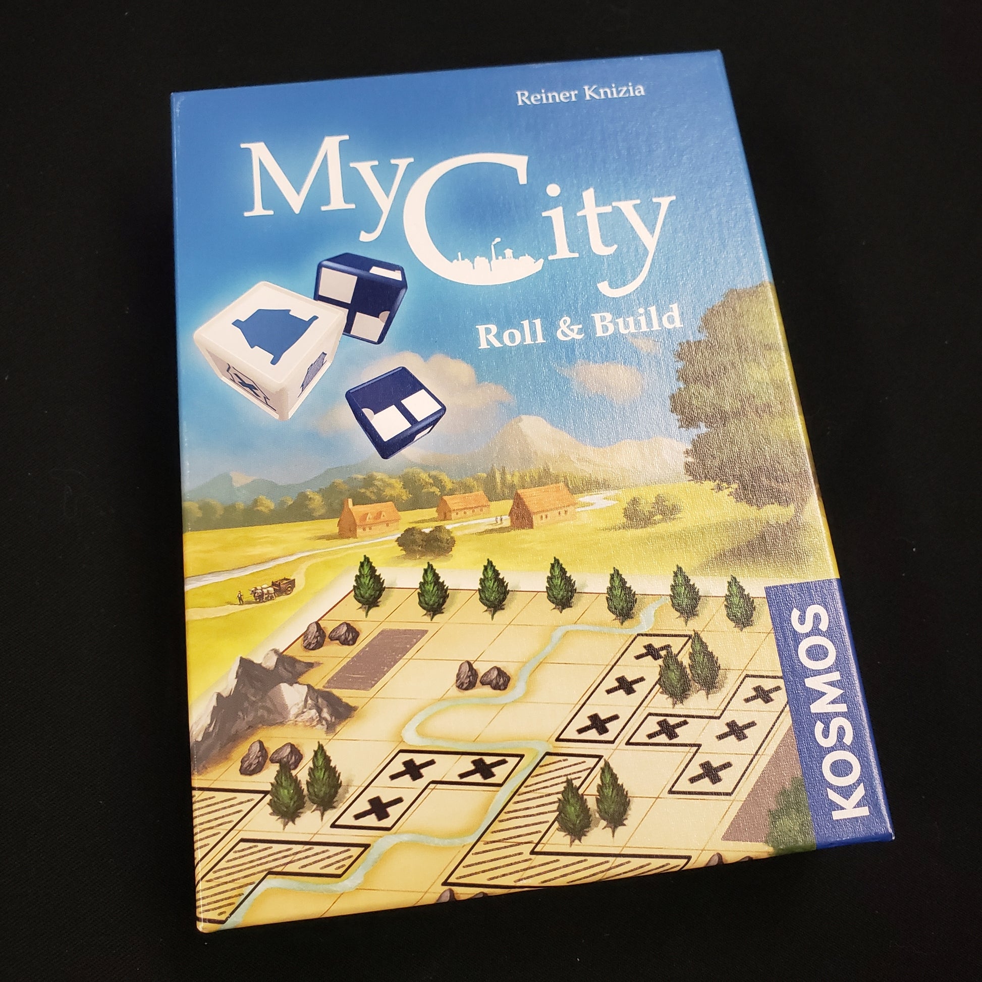 Image shows the front cover of the box of the My City: Roll & Build board game