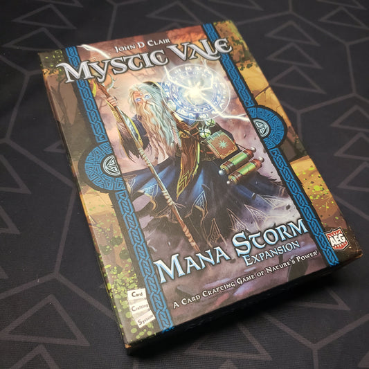Image shows the front cover of the box of the Mana Storm expansion for the card game Mystic Vale