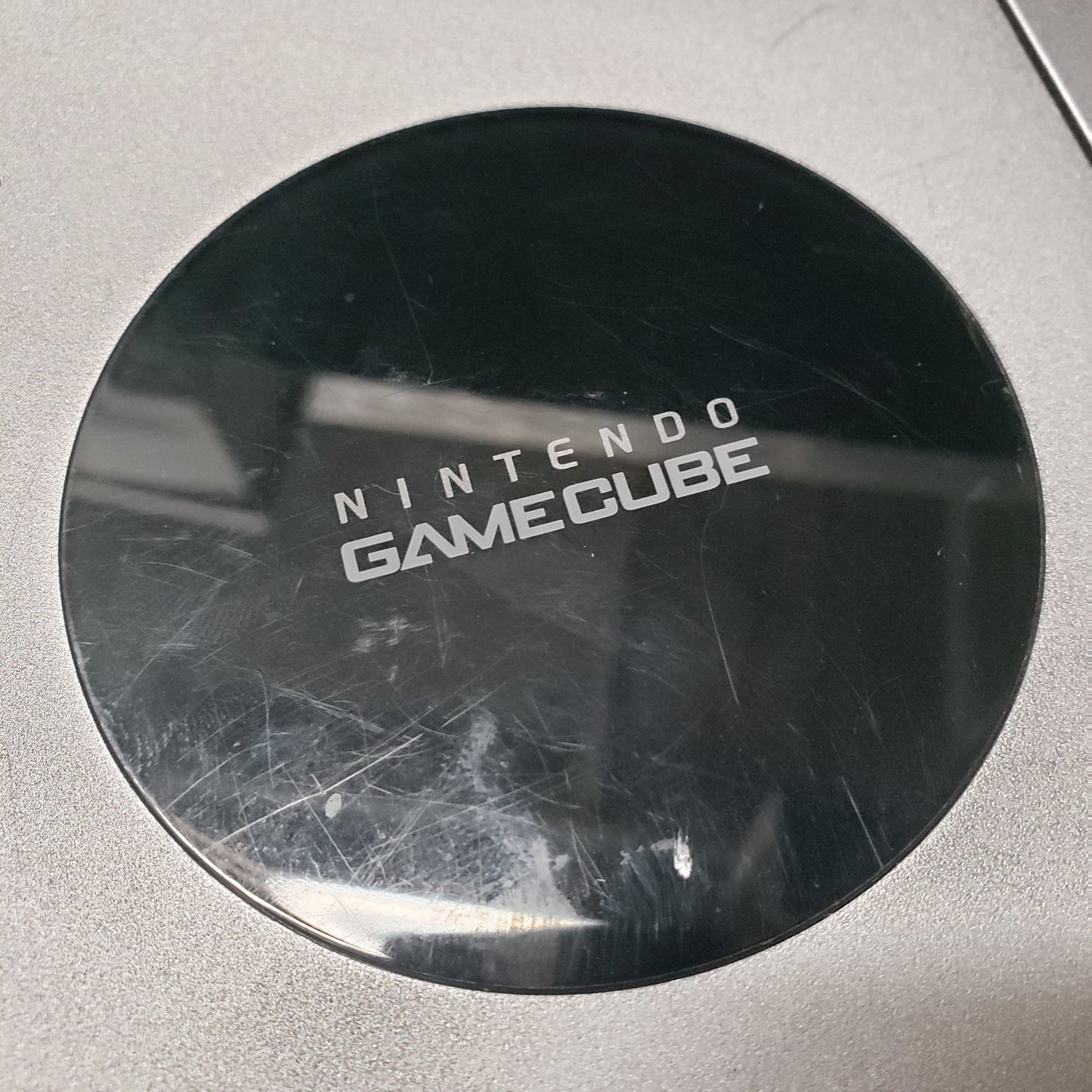 Image shows some light scratches on the glossy top part of a platinum color Nintendo GameCube gaming console