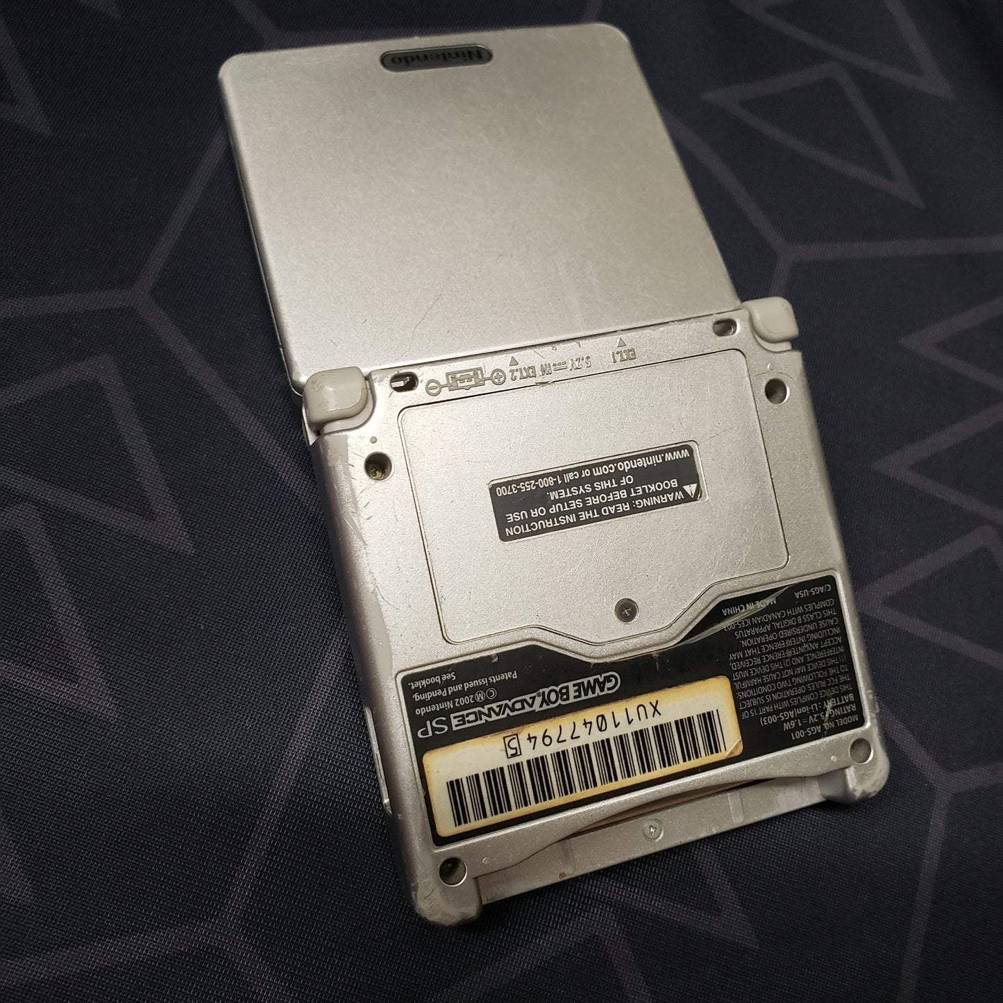 Image shows the back of a platinum Nintendo Game Boy Advance SP gaming console
