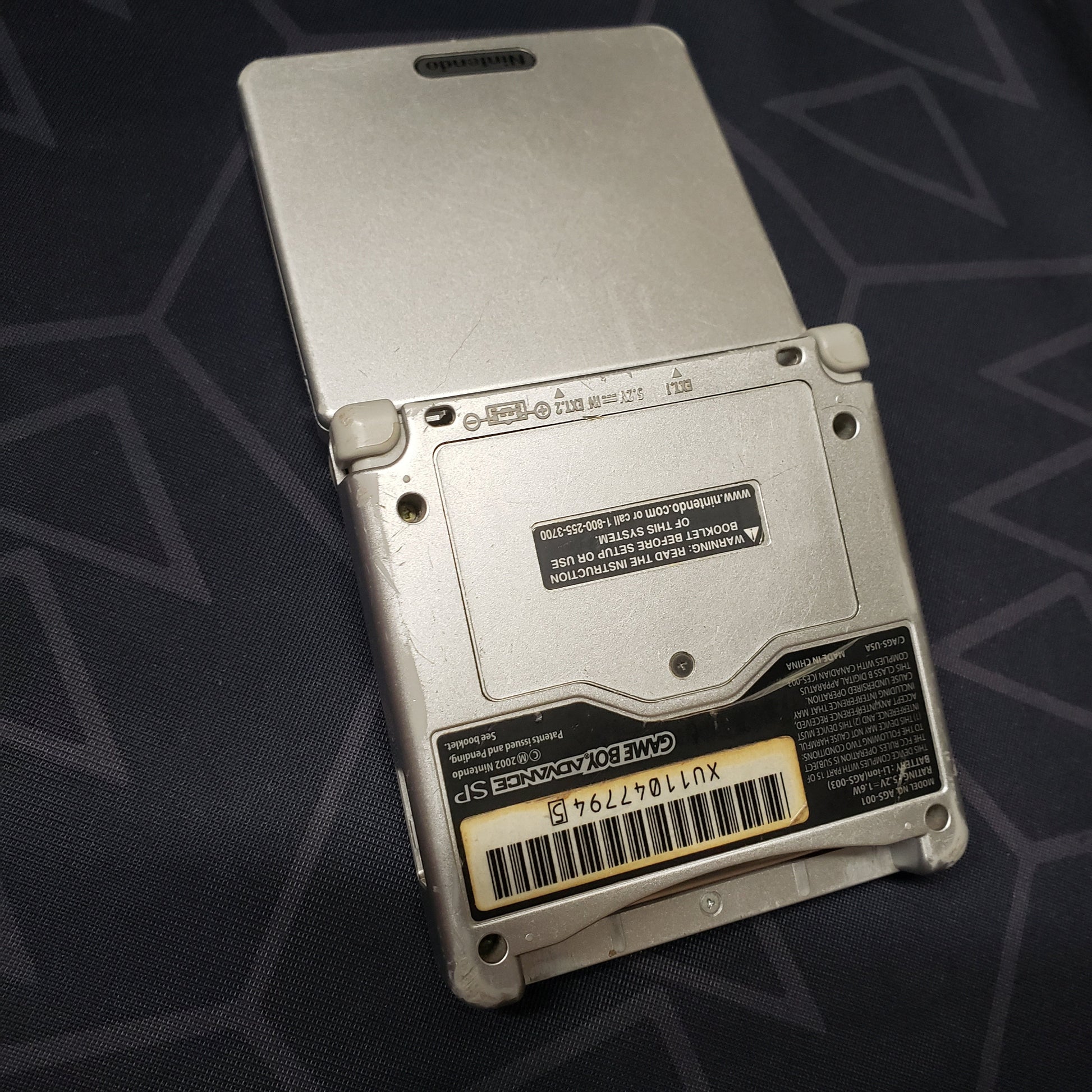 Image shows the back of a platinum Nintendo Game Boy Advance SP gaming console
