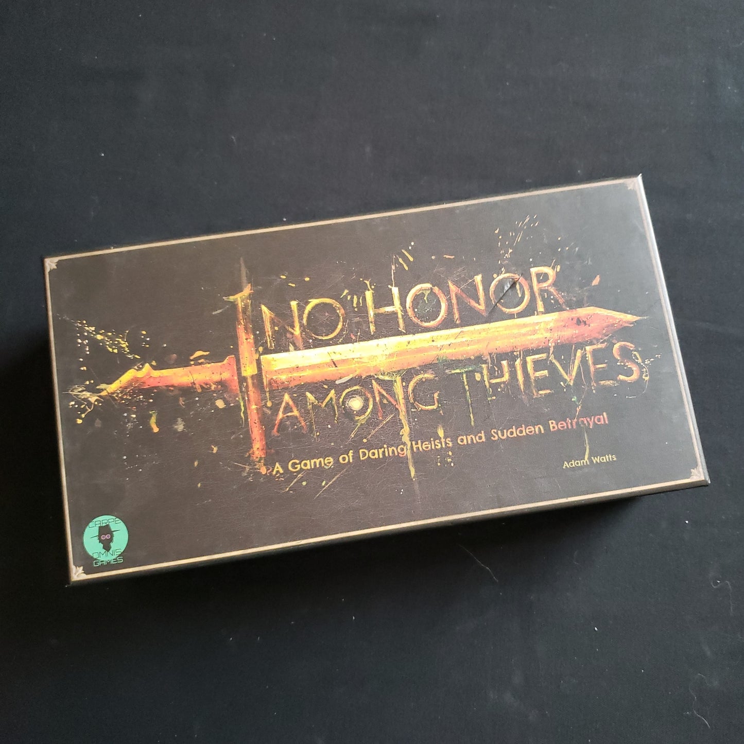 Image shows the front cover of the box of the No Honor Among Thieves card game