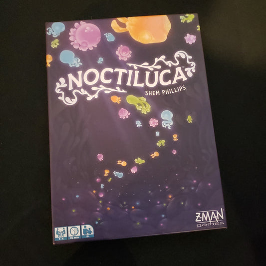 Image shows the front cover of the box of the Noctiluca board game