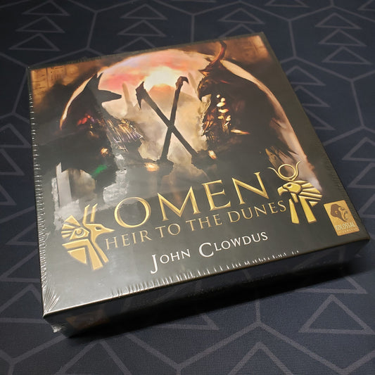 Image shows the front cover of the box of the Omen: Heir to the Dunes card game
