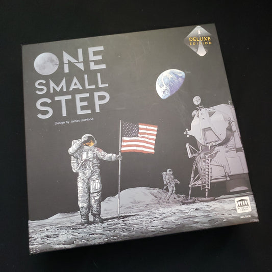 Image shows the front cover of the box of the One Small Step (Deluxe Edition board game