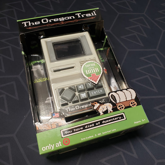 Image shows the front cover of the packaging of the Oregon Trail Handheld Game
