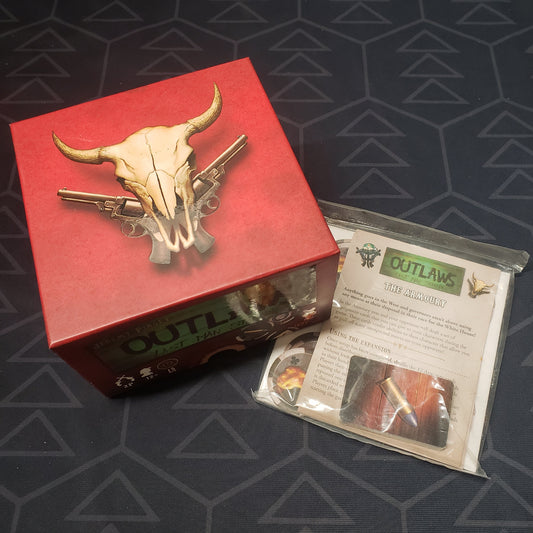 Image shows the front cover of the box for the Outlaws: Last Man Standing board game with "The Armoury" mini expansion sitting next to it in plastic