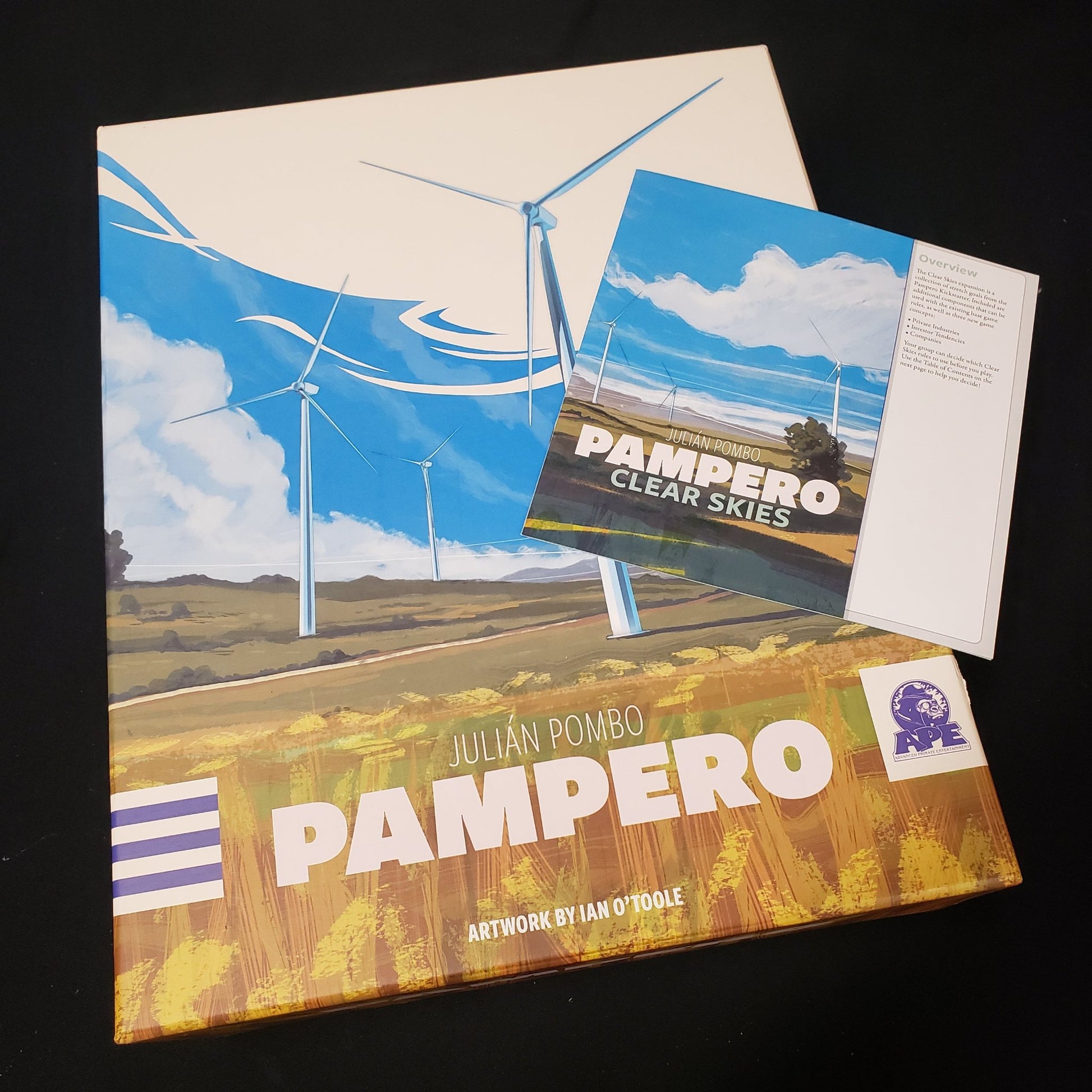 Image shows the front cover of the box of the Pampero board game with the instructions for the Clear Skies expansion sitting on top of it