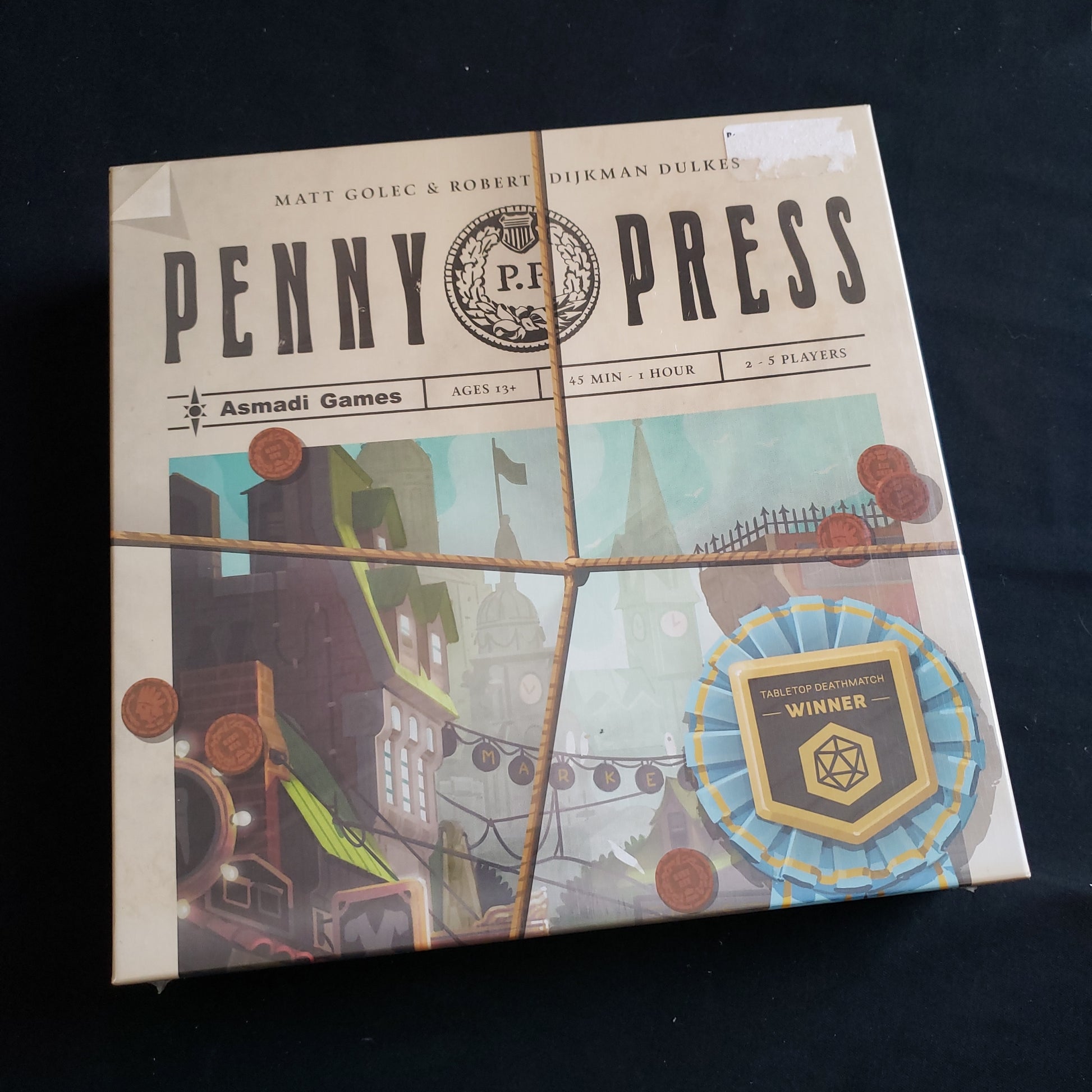 Image shows the front cover of the box of the Penny Press board game