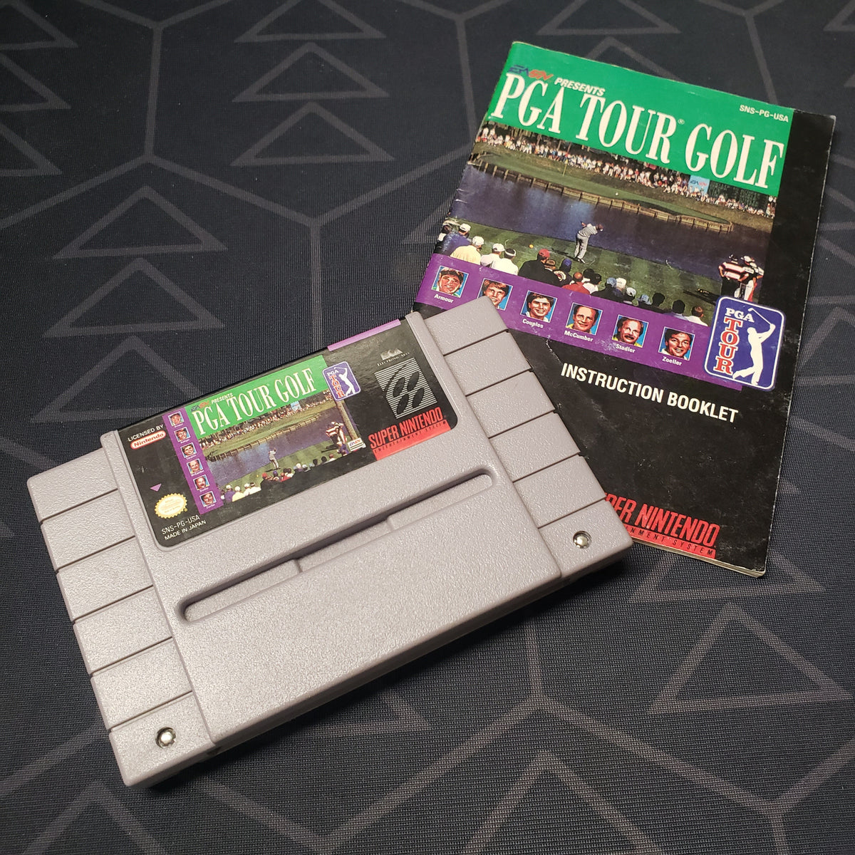Image shows the front of the cartridge  & the manual for the video game PGA Tour Golf for the Super Nintendo