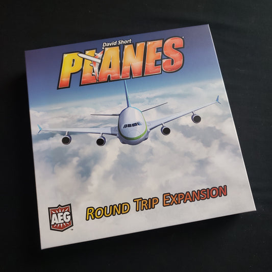 Image shows the front cover of the box of the Round Trip expansion for the Planes board game