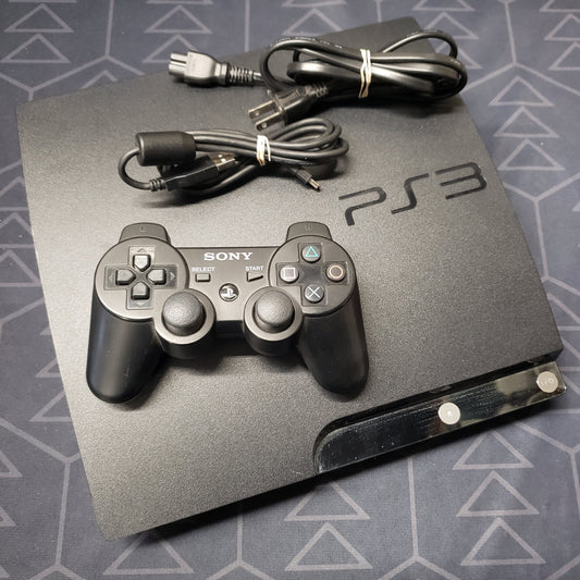 Image shows the top of a Playstation 3 Slim gaming console with a controller and cables sitting on top of it