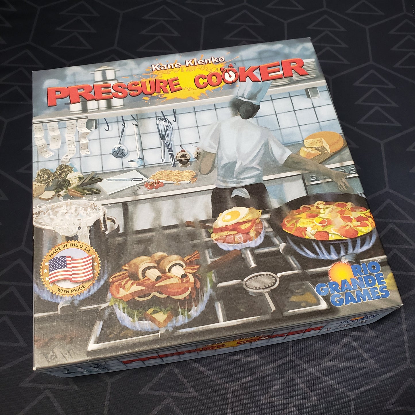 Image shows the front cover of the box of the Pressure Cooker board game