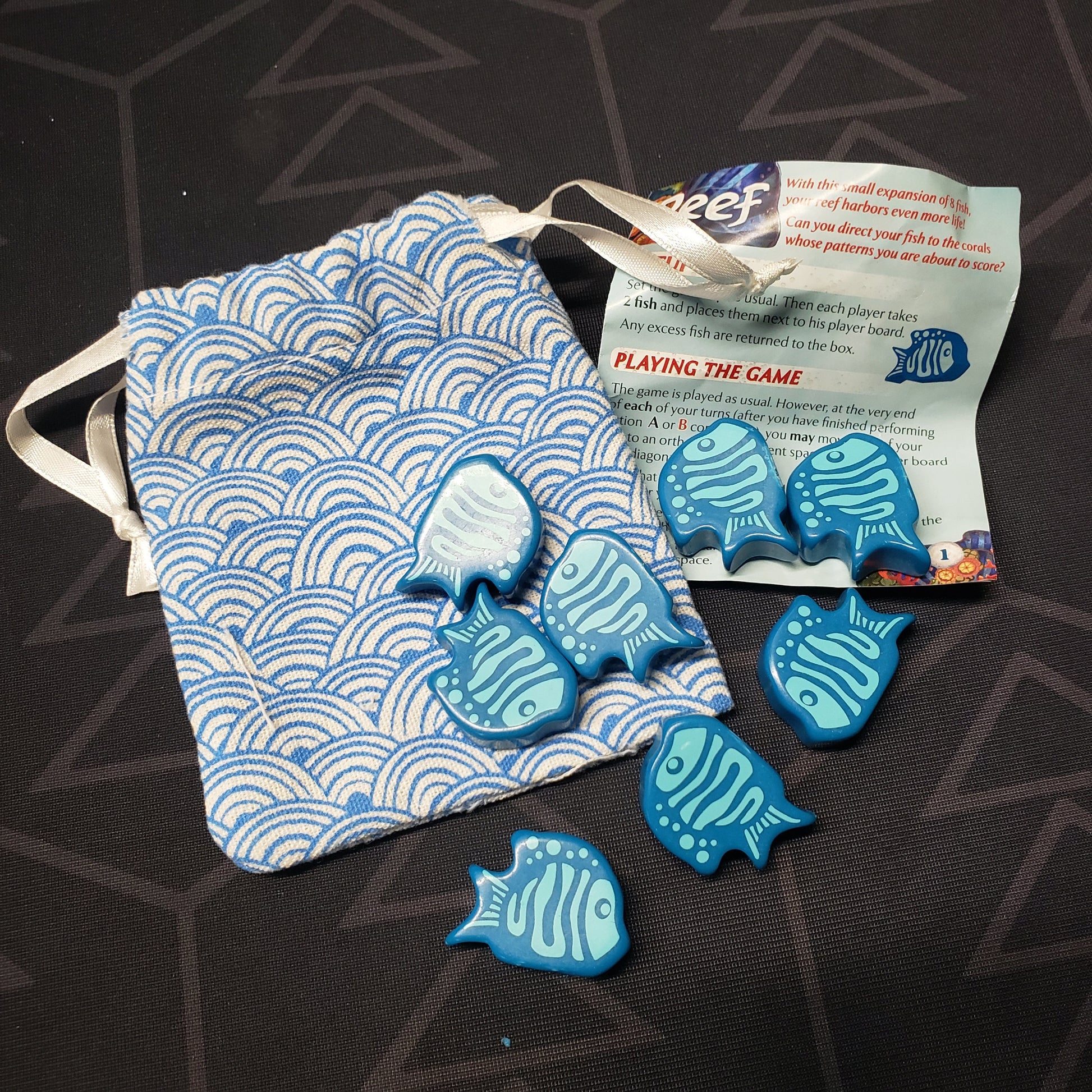 Image shows the bag, instructions and components for the Kings of the Coral mini expansion for the board game Reef