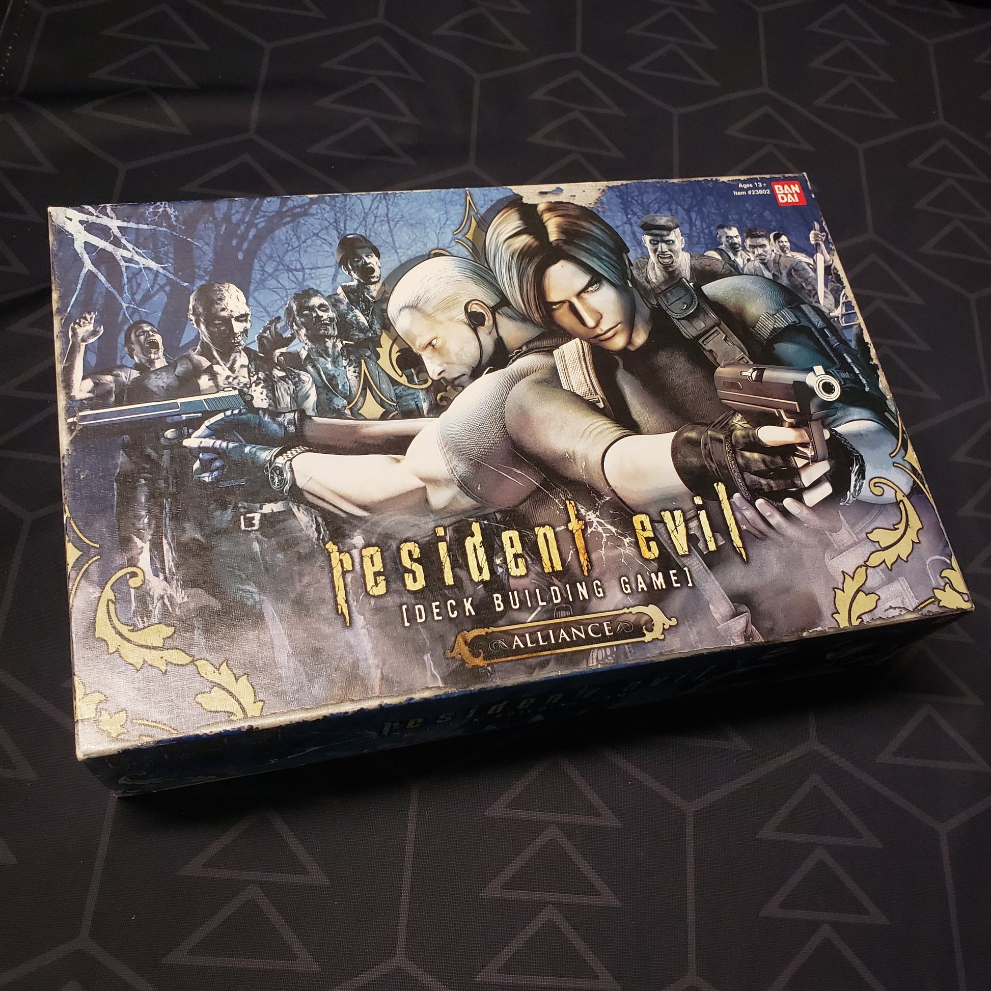 Image shows the front cover of the box for the Resident Evil Deck Building Game: Alliance card game