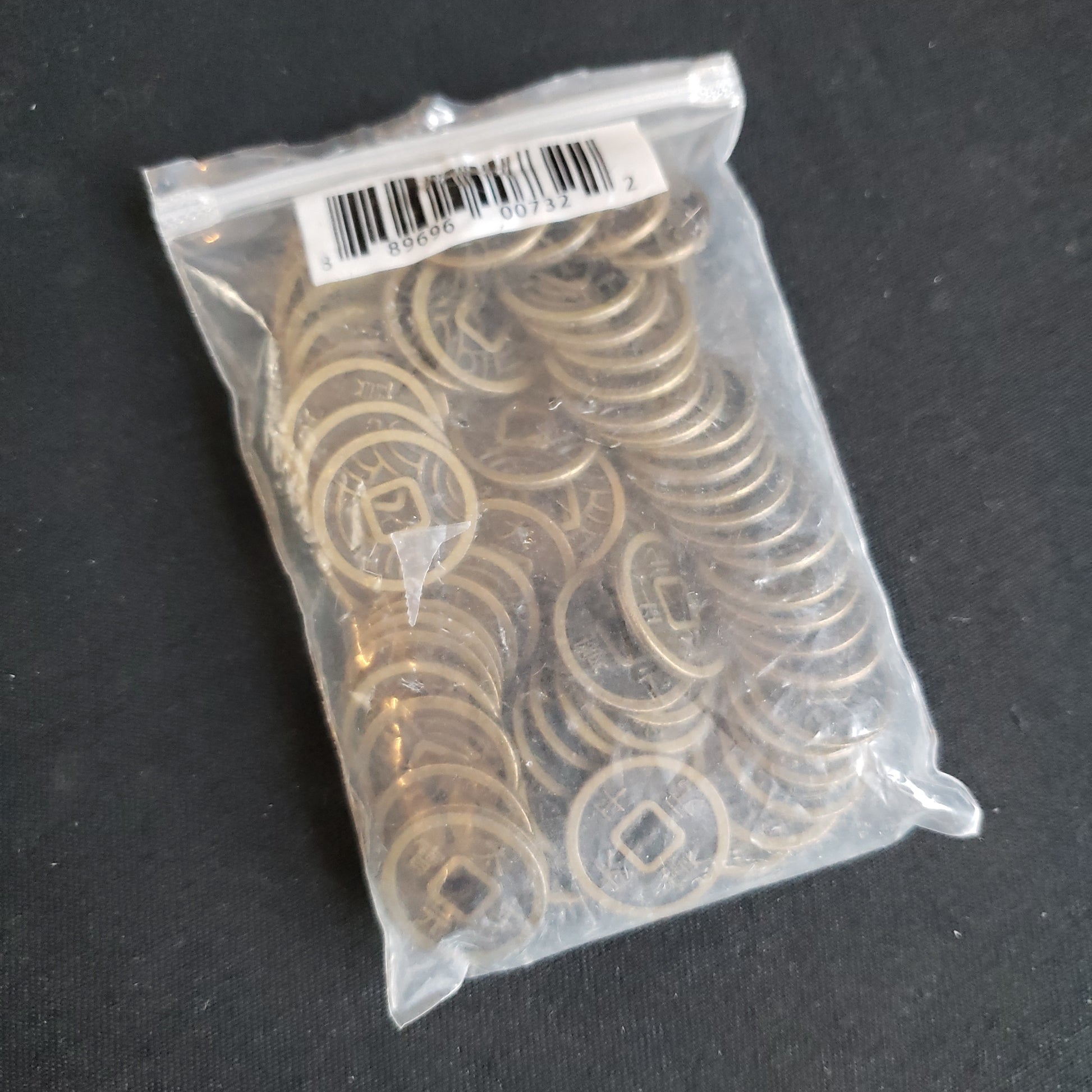 Image shows a clear plastic baggie with 65 metal coins for the Rising Sun board game in it
