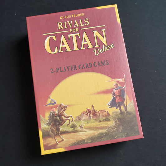 Image shows the front cover of the box of the Rivals for Catan: Deluxe card game