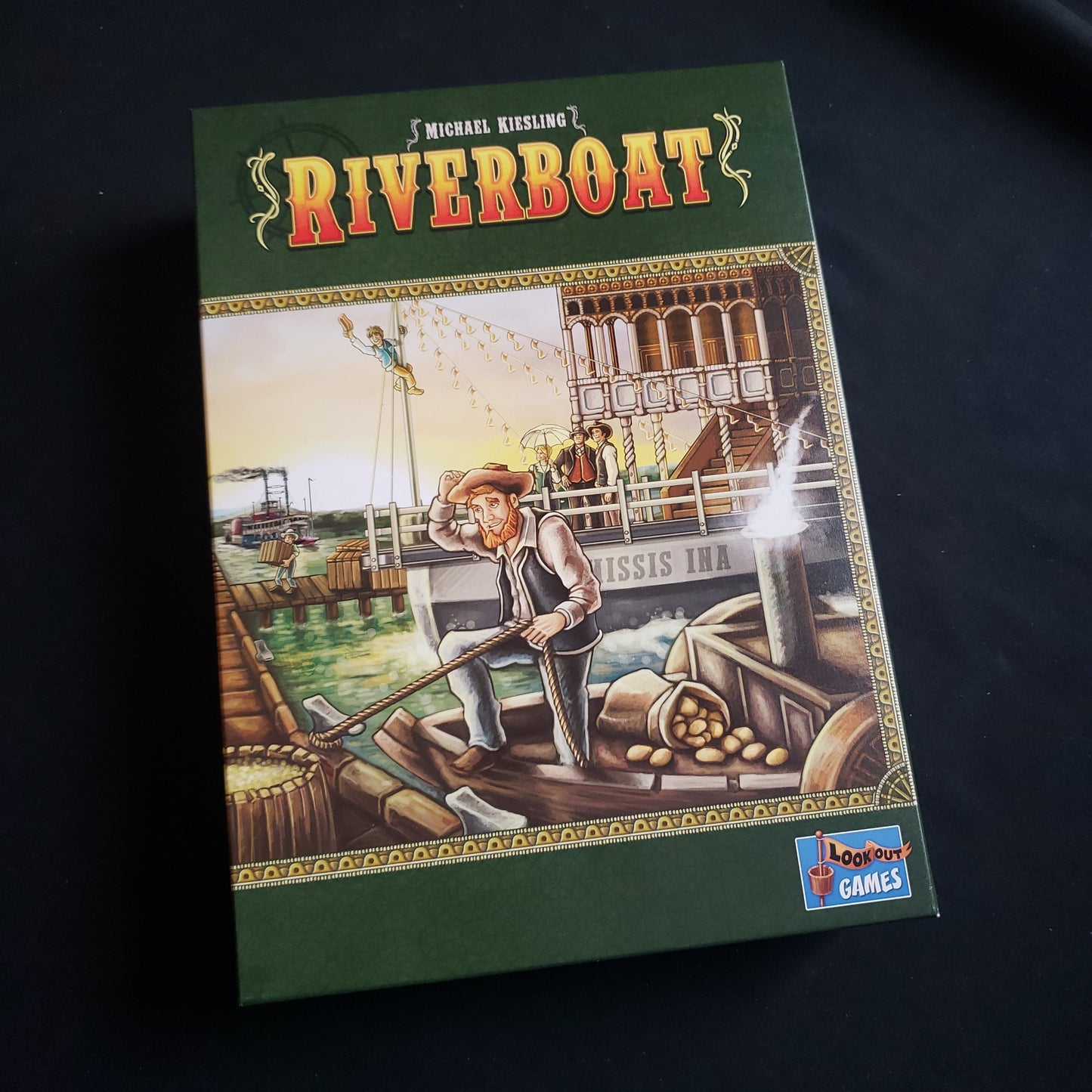 Image shows the front cover of the box of the Riverboat board game