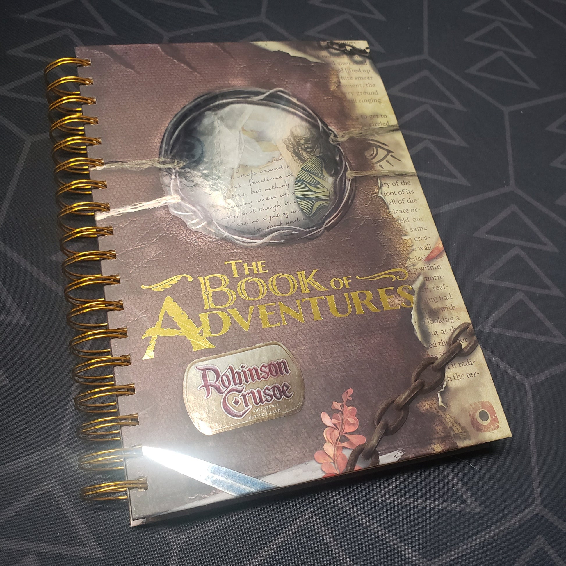 Image shows the front cover of the Book of Adventures scenario expansion book for the board game Robinson Crusoe