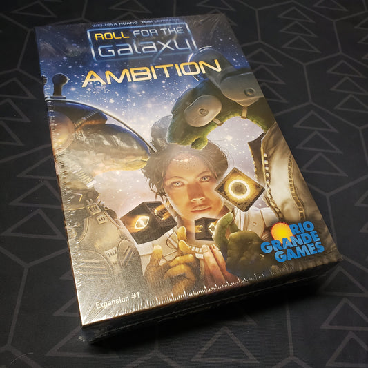 Image shows the front cover of the box of the Ambition expansion for the board game Roll for the Galaxy