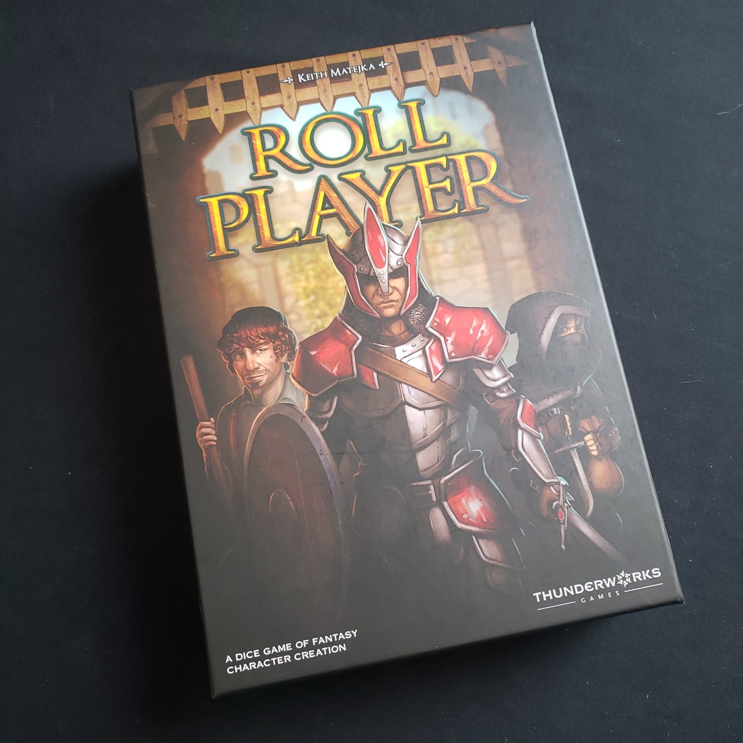 Image shows the front cover of the box of the Roll Player board game