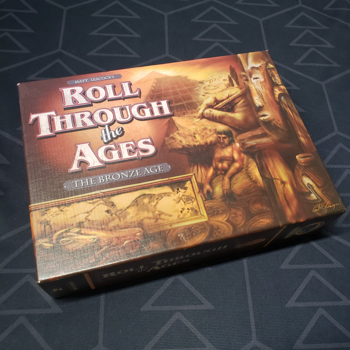 Image shows the front cover of the box for the board game Roll Through the Ages: The Bronze Age