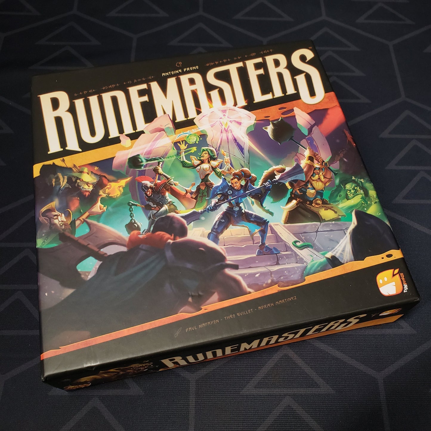 Image shows the front cover of the box of the Runemasters card game