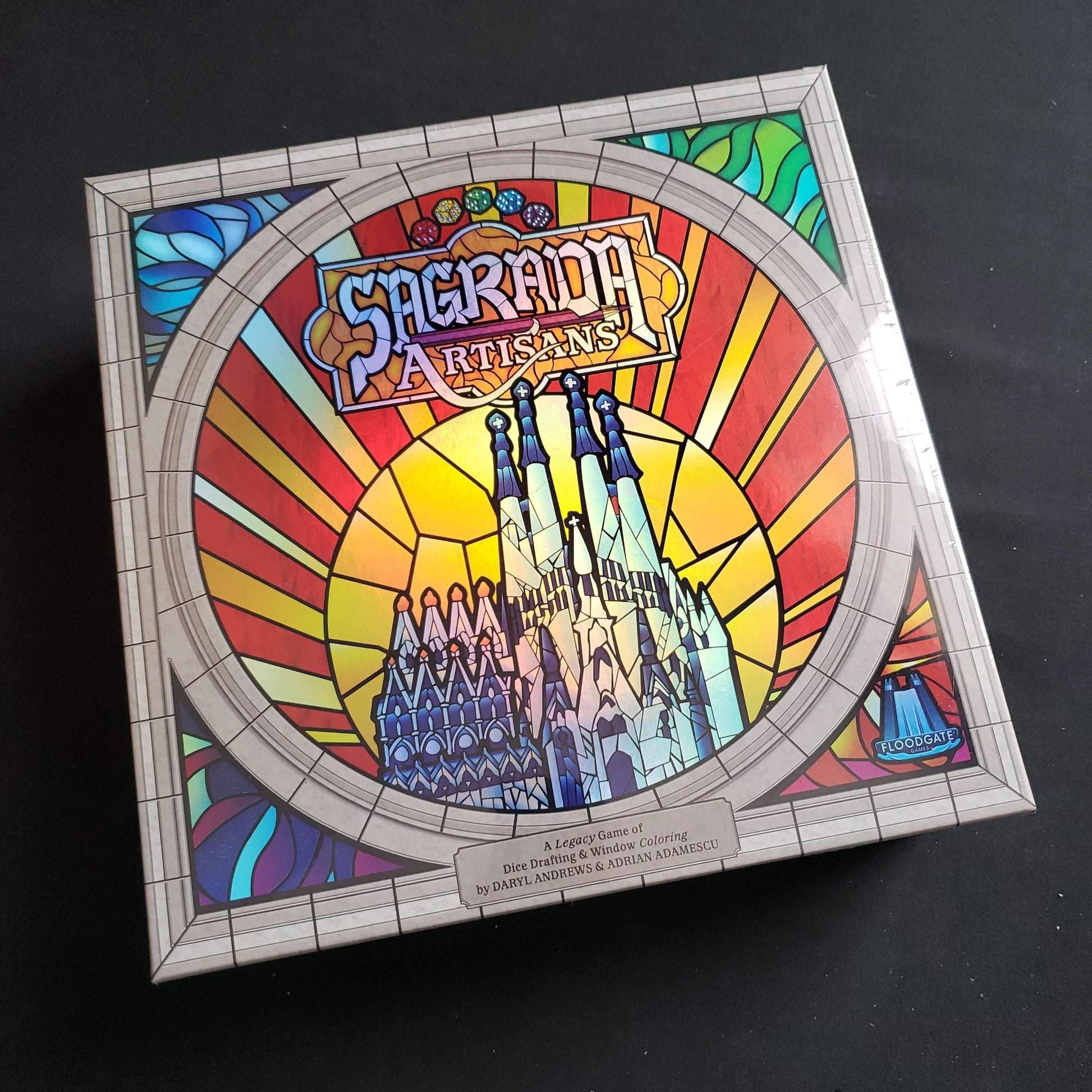 Image shows the front cover of the box of the Sagrada Artisans board game