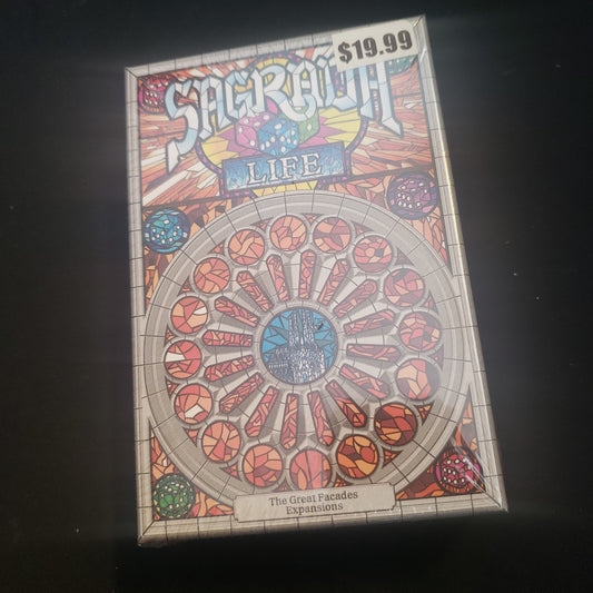 Image shows the front cover of the box of the Life expansion for the board game Sagrada