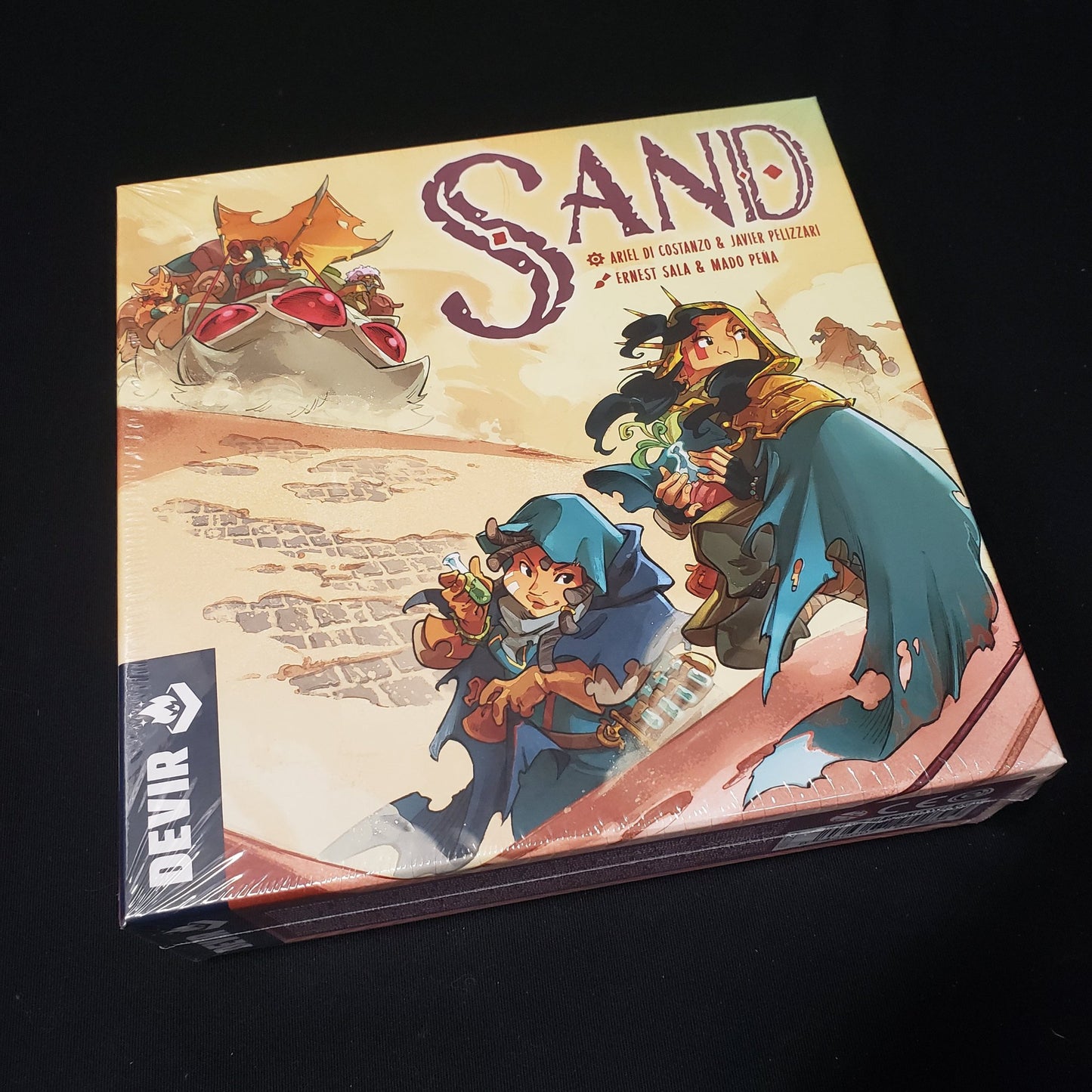 Image shows the front cover of the box of the Sand board game