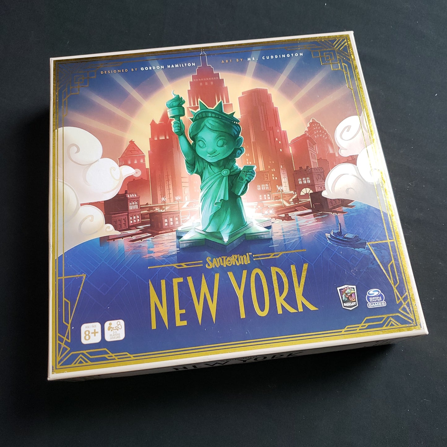 Image shows the front cover of the box of the Santorini: New York board game