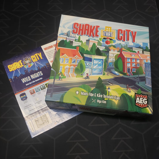 Image shows the front cover of the box of the Shake That City board game sitting on top of the instructions for the Wild Nights expansion