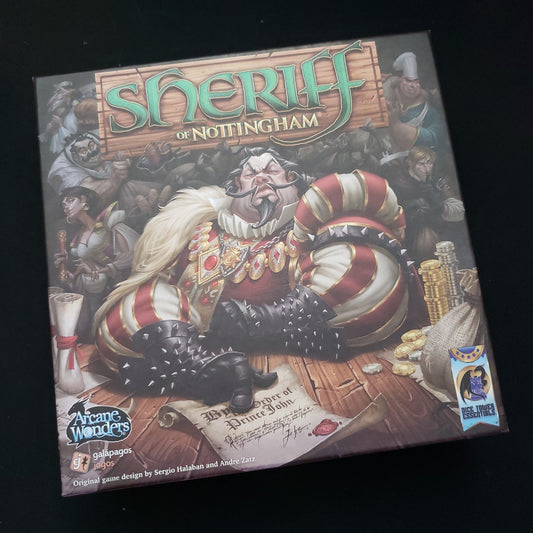 Image shows the front cover of the box of the Sheriff of Nottingham board game, with the instructions for the Merry men expansion sitting on top of it