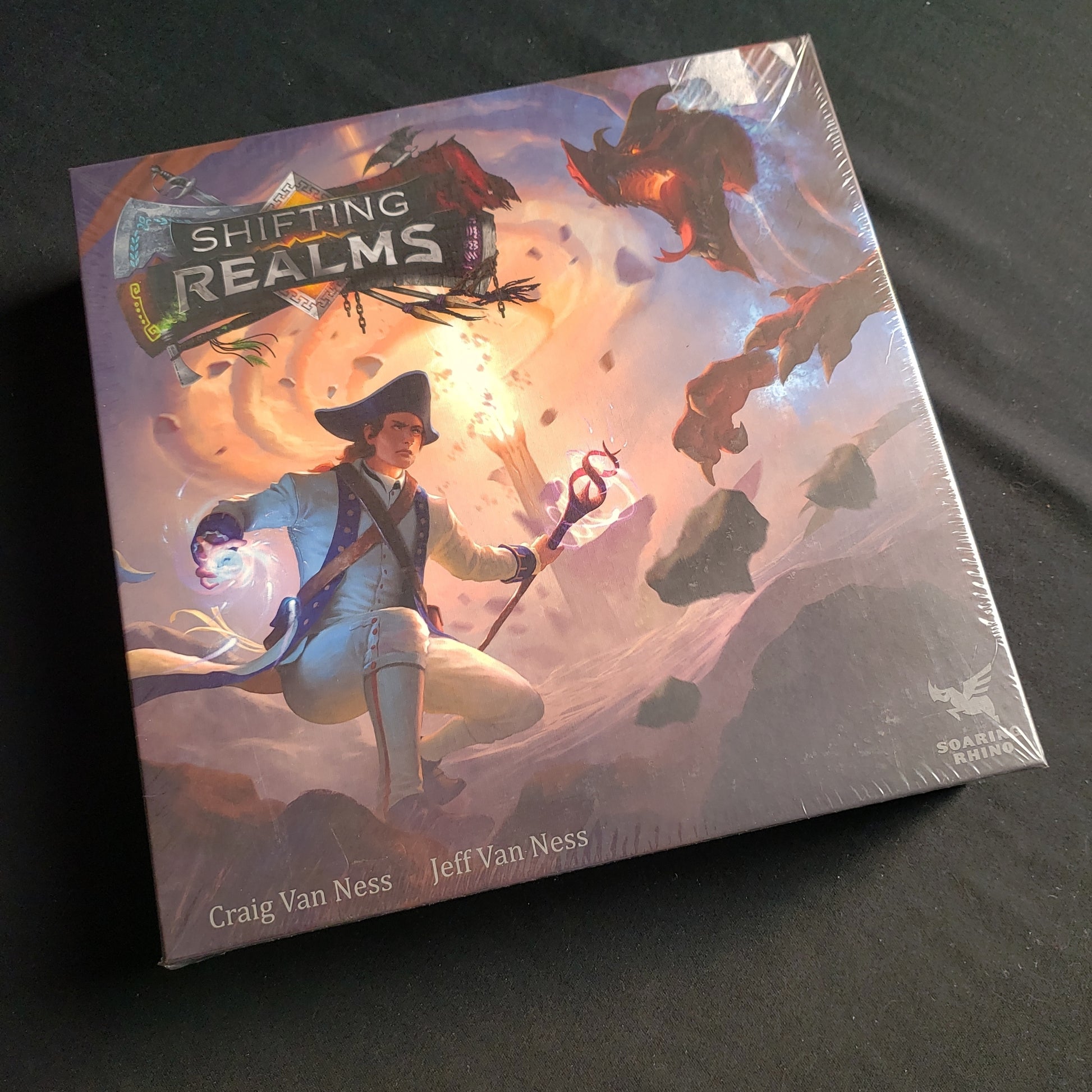 Image shows the front cover of the box of the Shifting Realms board game