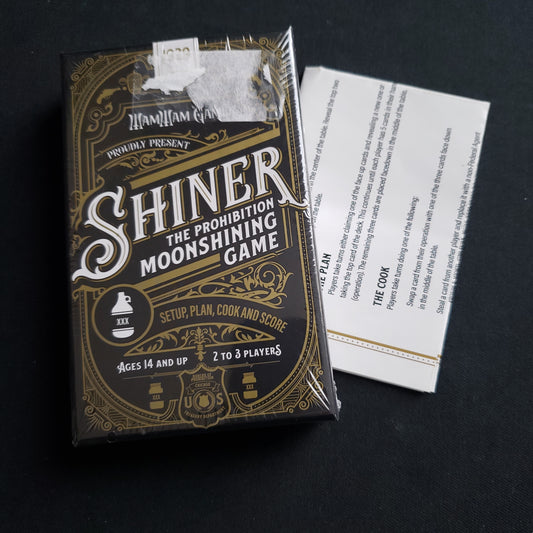 Image shows the front cover of the box of the Shiner card game, with the instructions for it underneath