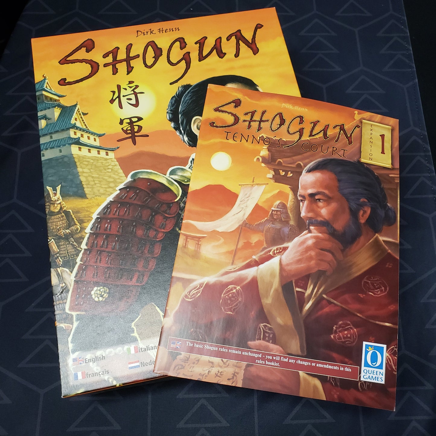 Image shows the front cover of the box for the Shogun board game with the instructions for the Tenno's Court expansion sitting on top of it